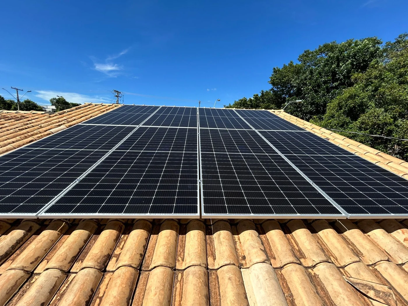 Painéis solares alinhados sobre telhas cerâmicas sob céu azul